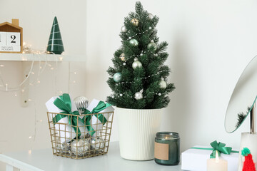 Small Christmas tree with presents on shelf in light room