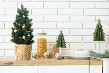 Small Christmas tree on counter near white brick wall in kitchen, closeup