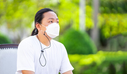 A man wearing white T shirt and white mask is sitting calm on the armchair with his arms on the...