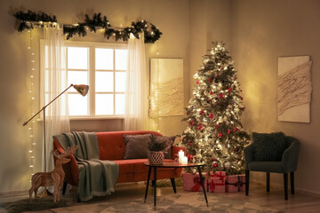 Interior of dark living room with glowing Christmas tree, sofa and armchair