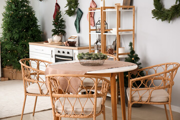 Dining table with Christmas branches in interior of kitchen