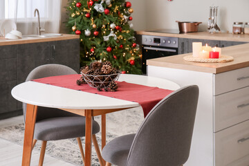Dining table with fir cones in kitchen decorated for Christmas