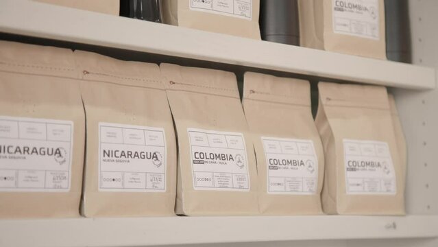 Assorted roasted coffee beans packaged in bags displayed in modern local coffee shop for retail.