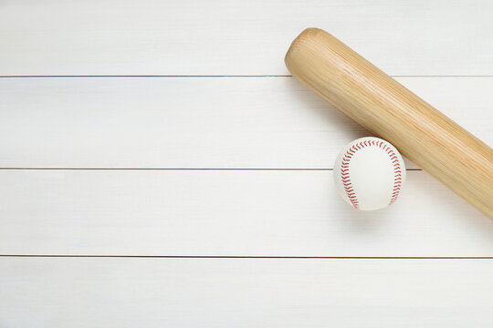 Baseball bat and ball on white wooden table, top view with space for text. Sports equipment