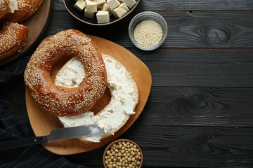 Delicious bagel with tofu cream cheese and soy beans on black wooden table, flat lay. Space for text