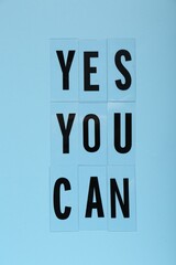 Phrase Yes You Can of plastic letters on light blue background, top view. Motivational quote