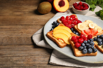 Tasty toasts with different spreads and fruits on wooden table. Space for text