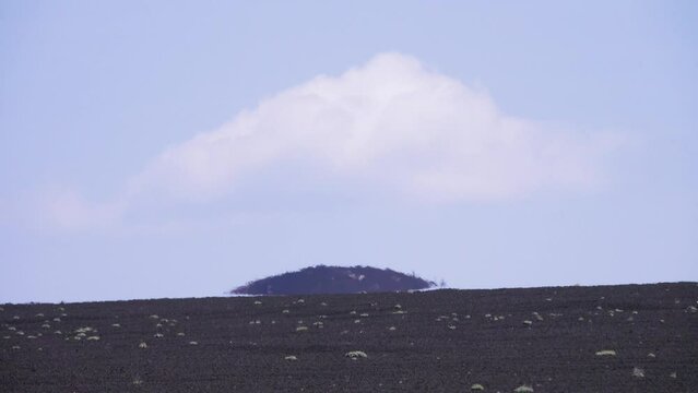 Superior mirage (loom). Volcanic arctic black desert at a hot summer day. Volcanic black ash is strongly heated by the sun's rays and there is a strong haze. Fata Morgana of volcanic cone. Kamchatka