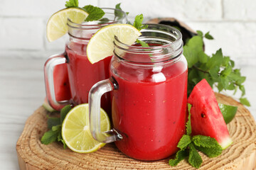 Tasty summer watermelon drink, limes and mint on white wooden table, closeup
