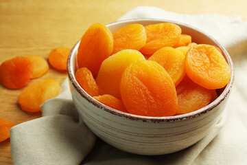 Bowl of tasty apricots on wooden table, closeup. Dried fruits