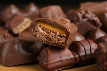 Many tasty chocolate bars on wooden board, closeup