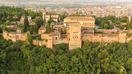 Sunrise aerial photo of the Alhambra fortress in Granada, Spain. The fortress is bathed in golden...