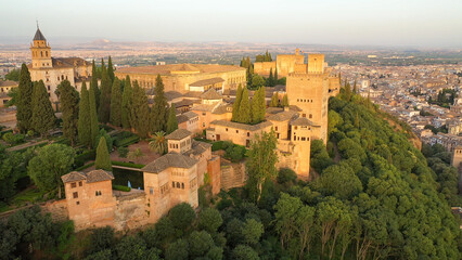 Obraz premium Sunrise aerial side view photo of the Alhambra fortress in Granada, Spain. The fortress is bathed in golden light.