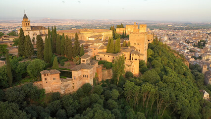 Fototapeta na wymiar Sunrise aerial side view photo of the Alhambra fortress in Granada, Spain. The fortress is bathed in golden light.