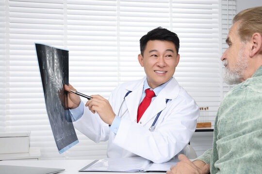 Happy doctor showing MRI images to senior patient in hospital
