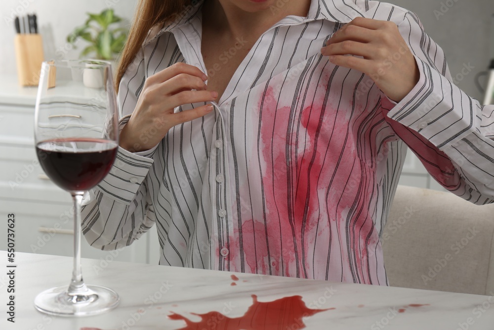 Wall mural Woman with spilled wine over her shirt and marble table in kitchen, closeup