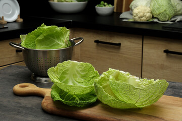 Fresh Savoy cabbage leaves on black table in kitchen