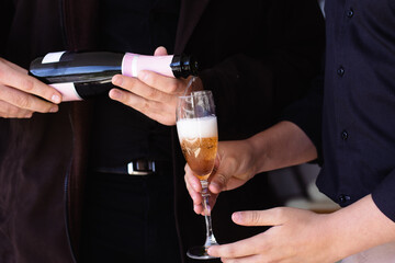 Close-up of two men's hands serving a glass of champagne to toast for a happy new year, valentine's day, wedding, business celebration