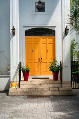 Fototapeta na wymiar Orange double front doors with arched transom window and potted plants at the front- Miami, Florida