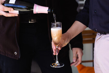 Close-up of two men's hands serving a glass of champagne to toast for a happy new year, valentine's day, wedding, business celebration