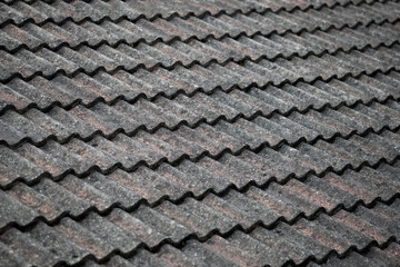 Cement roof tiles. Gray colored tiled roof. Old house roofing, gray concrete tiles showing years of exposure to the elements