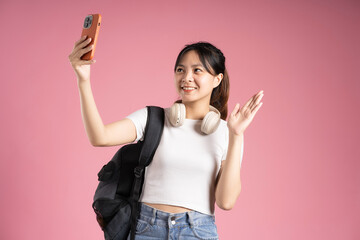 Obraz na płótnie Canvas image of asian girl student holding phone and isolated on pink background