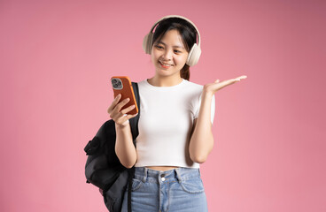 image of asian girl student holding phone and isolated on pink background