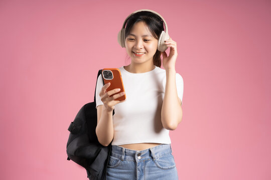 image of asian girl student holding phone and isolated on pink background