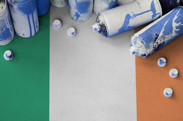 Ireland flag and few used aerosol spray cans for graffiti painting. Street art culture concept,...
