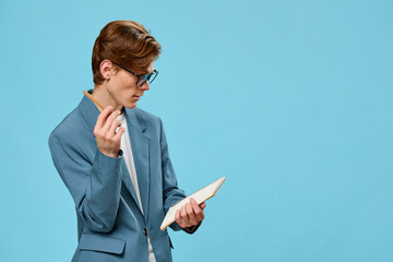 pensive cute guy in a jacket and glasses on a blue background
