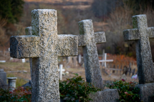 An image of three very old and weathered concrete stone crosses in an old graveyard. 