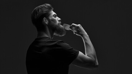 Stylish man brushing his beard and moustache. Bearded man with hair brush on black background....