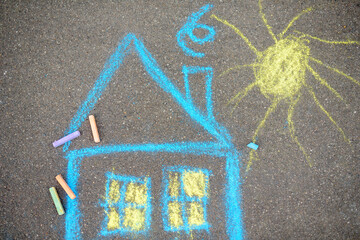 Chalk picture of house and sun on asphalt of sidewalk. Kids creative picture on gray background of...