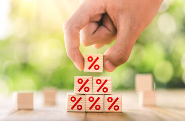 Interest rate financial and mortgage rates concept. Hand putting wood cube block increasing on top with icon percentage symbol upward direction. business concept of investment interest rates appraisal