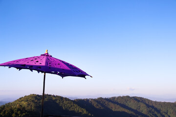 Big purple fabric umbrella on  blue sky and mountain view outdoor background