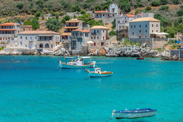 Obraz premium view of Limeni village with fishing boats in turquoise waters and the stone buildings as a background in Mani, South Peloponnese , Greece.