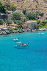 Obraz premium view of Limeni village with fishing boats in turquoise waters and the stone buildings as a background in Mani, South Peloponnese , Greece.