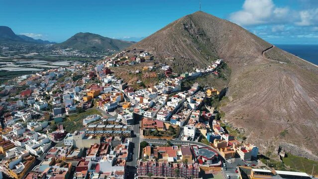 Cinematic aerial shot in orbit over the city of Galdar and the Galdar mountain. On a sunny day on the island of Gran Canaria, Spain.
