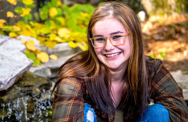 Happy girl with torn jeans and a flannel shirt poses for 
 a n ooutdoor  portrait