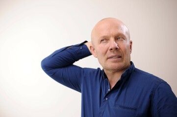 Obraz premium Emotions of an adult handsome bald man Doubt A man doubts what they say or he does not believe Experience anxiety caution How can it happen