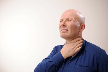 Emotions of an adult handsome bald man Sore throat man holding his hand to his throat he can't...
