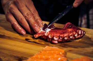 Close up of Chef cook hands chopping octopus for traditional Asian cuisine with Japanese knife....