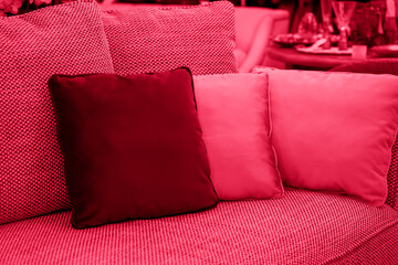 image toned in color of year 2023 viva magenta. cushions on cozy red sofa. Pillows on casual couch in the living room