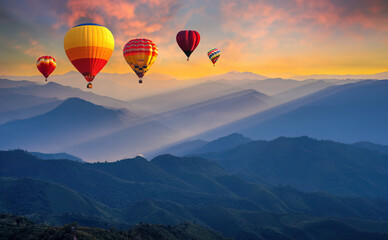 Fototapeta premium Colorful hot air balloons flying above high mountain at sunrise with beautiful sky background. aerial from Doi Pui Co, Mae Hong Son in Thailand