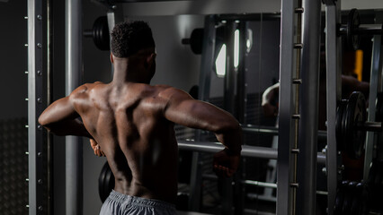 Fototapeta na wymiar Handsome afro american man posing showing back muscles in gym. 