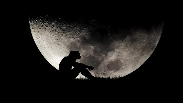 Lonely man with large moon in the background. hopeless loneliness concept