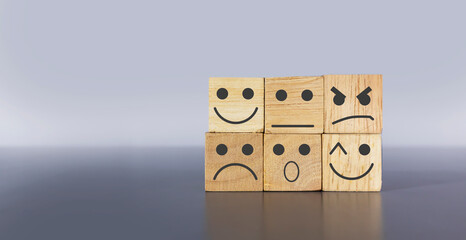 Character icons with different expressions on a wooden box on a light gray background.,emotional psychology
