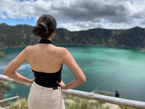 WOMAN LOOKING AT A LAGOON WITH HANDS ON WAIST