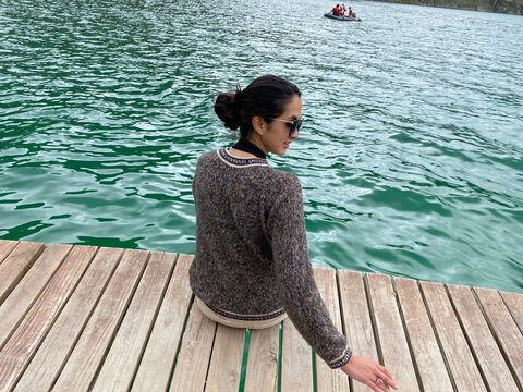 BLACK HAIRED WOMAN SITTING ON A PIER