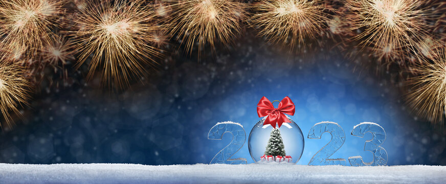 New Year card with ice number 2023 on snow. Toy in the form of a ball with a Christmas tree and gifts inside in the form of a bomb. Festive banner with salutes against the background of night abstract